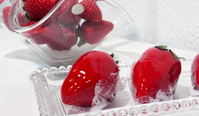 Uma cesta de morangos frescos e três morangos do amor caramelados