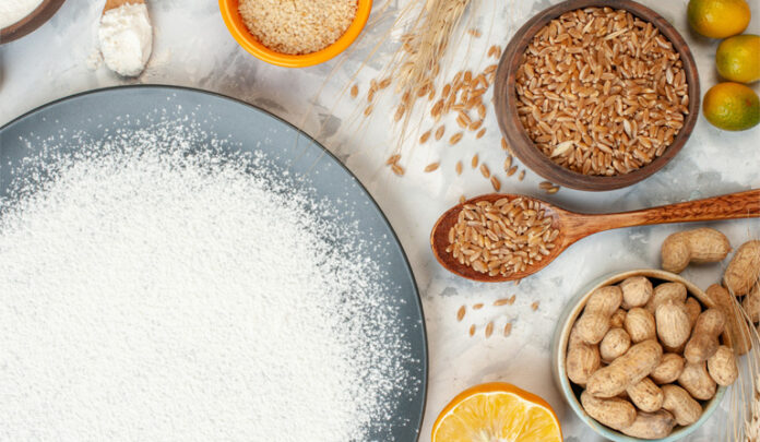 Mesa vista de cima, com tapioca (opção sem glúten) num prato e ao redor, arroz integral, grão-de-bico, quinoa e limões.