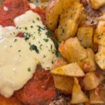 Beringela à Parmegiana: beringela empanada, crocante, acompanhada do molho artesanal da casa com queijo muçarela, acompanhado de batatas rústicas da casa