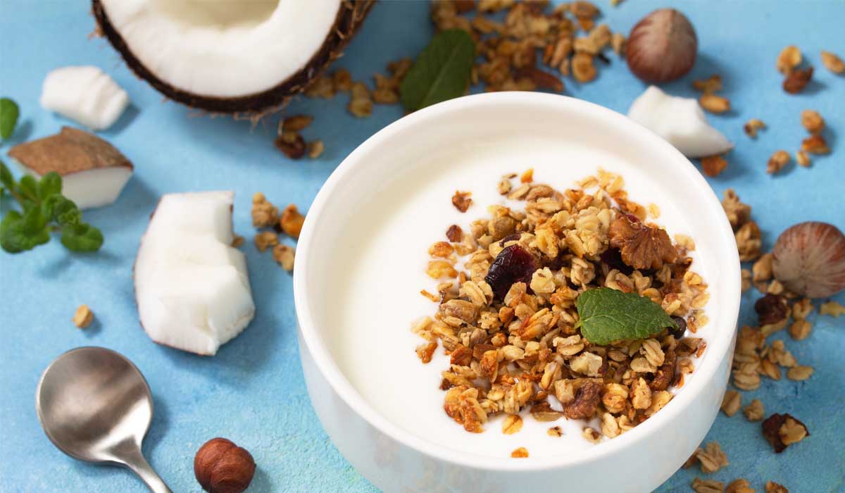 Iogurte de coco com granola caseira sem glúten feita de flocos de coco, sementes de abóbora e mel, com berries frescas, café da manhã saudável, 280 calorias