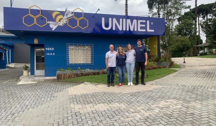 Álvaro, Jackeline, Alexandra e Gabriel em frente à fachada azul da Unimel, em Curitibaazul da Unimel, em Curitiba