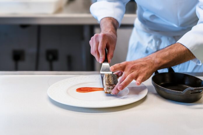 Chef finalizando um prato refinado numa cozinha profissional